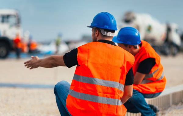Two transport workers on a construction site with helmet and safety jacket